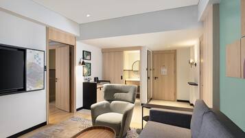 A modern living room with a sofa, armchair, and a flat-screen TV mounted on the wall.