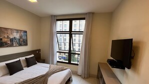 A hotel room with a bed, a television, a painting, and a window with curtains. - Jacques Pilon Residence (Centro Histórico de São Paulo São Paulo)