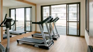 A gym with treadmills and a stationary bike, large windows, and a wooden floor. - Jacques Pilon Residence (Centro Histórico de São Paulo São Paulo)