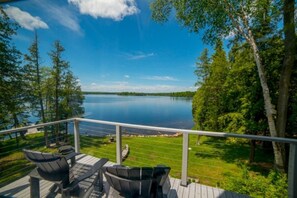 Um terraço com mobiliário para áreas externas, com vista para um lago, rodeado por árvores.