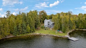 A lakeside cabin with a dock, surrounded by dense forest.