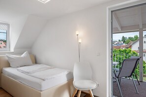 Ein Schlafzimmer mit Bett, Stuhl, Stehlampe und einem Balkon mit Tisch und Stühlen.