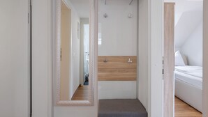 Moderni hotellihuone, jossa on puinen penkki, peili ja sänky.