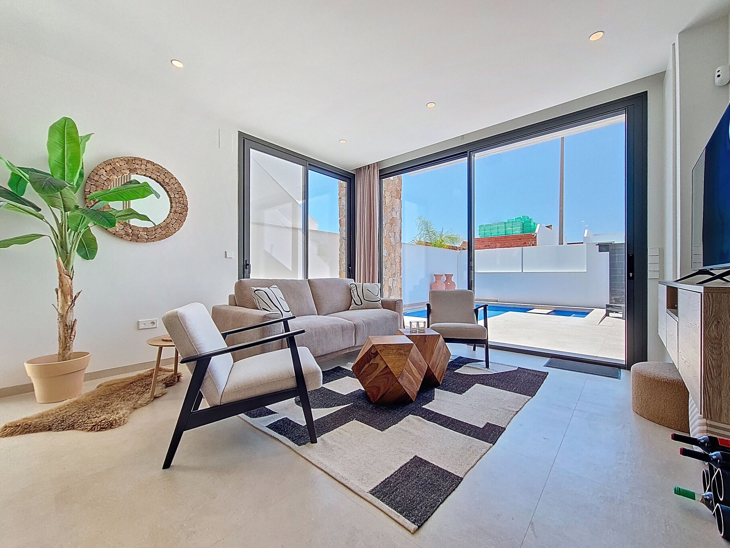 Uma sala de estar moderna com sofá, poltrona e uma grande planta em vaso.