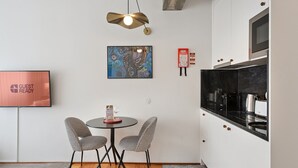 A compact kitchen with a dining area, a flat-screen TV, and a modern pendant light. - GuestReady – A welcoming space to unwind (Porto)