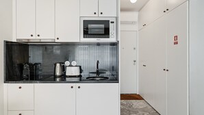A compact kitchen with white cabinets, a microwave, a toaster, and a kettle. - GuestReady – A welcoming space to unwind (Porto)