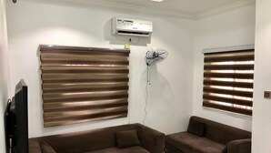 Een woonkamer met twee bruine banken, een zwarte salontafel en een airconditioning op de muur.