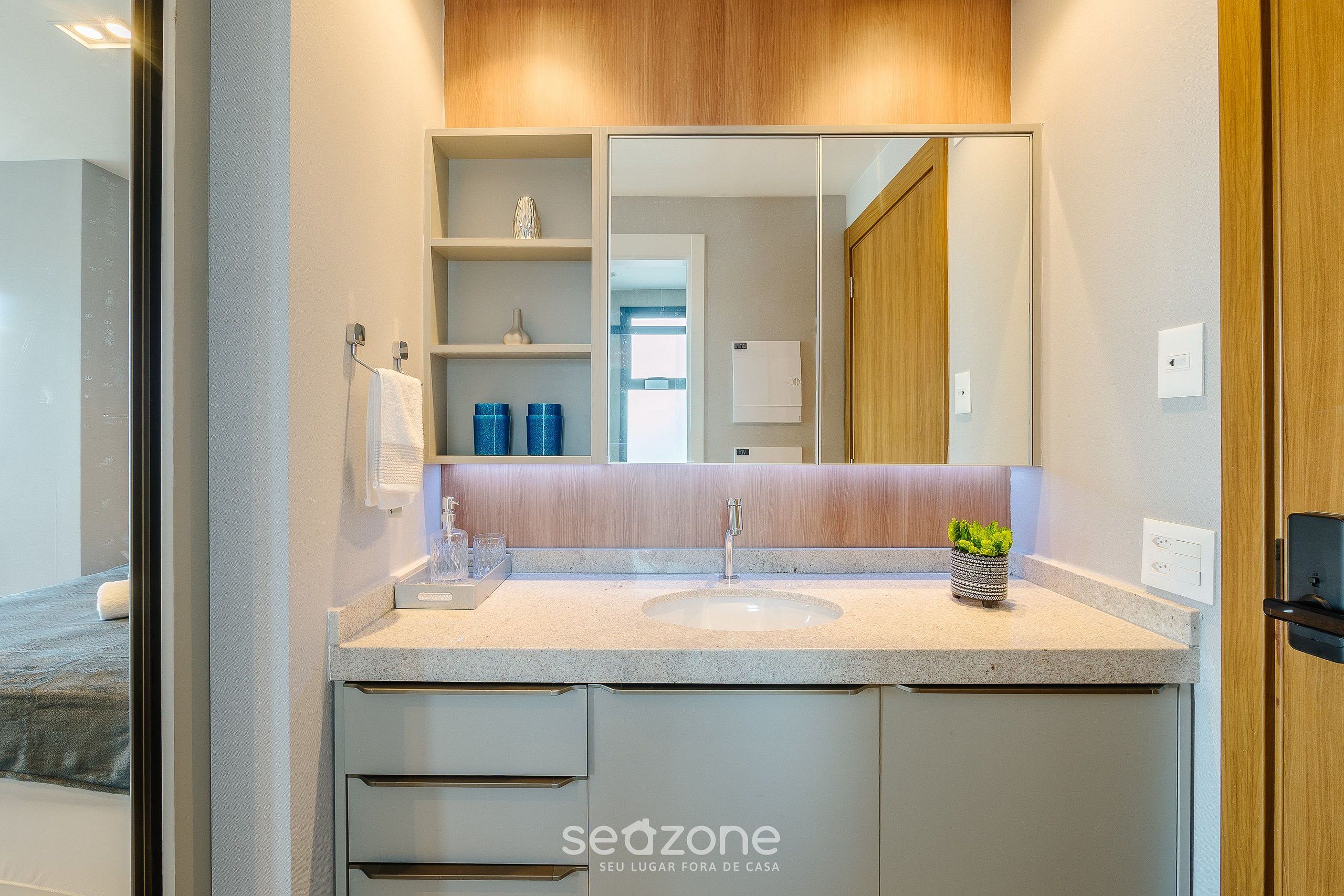 A modern bathroom with a large mirror, a sink, and built-in shelves.