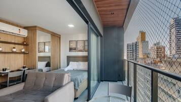 Una camera d'albergo moderna con balcone, un letto, un divano e un'area pranzo.