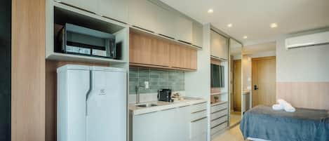A compact kitchenette with a refrigerator, microwave, and a coffee maker.
