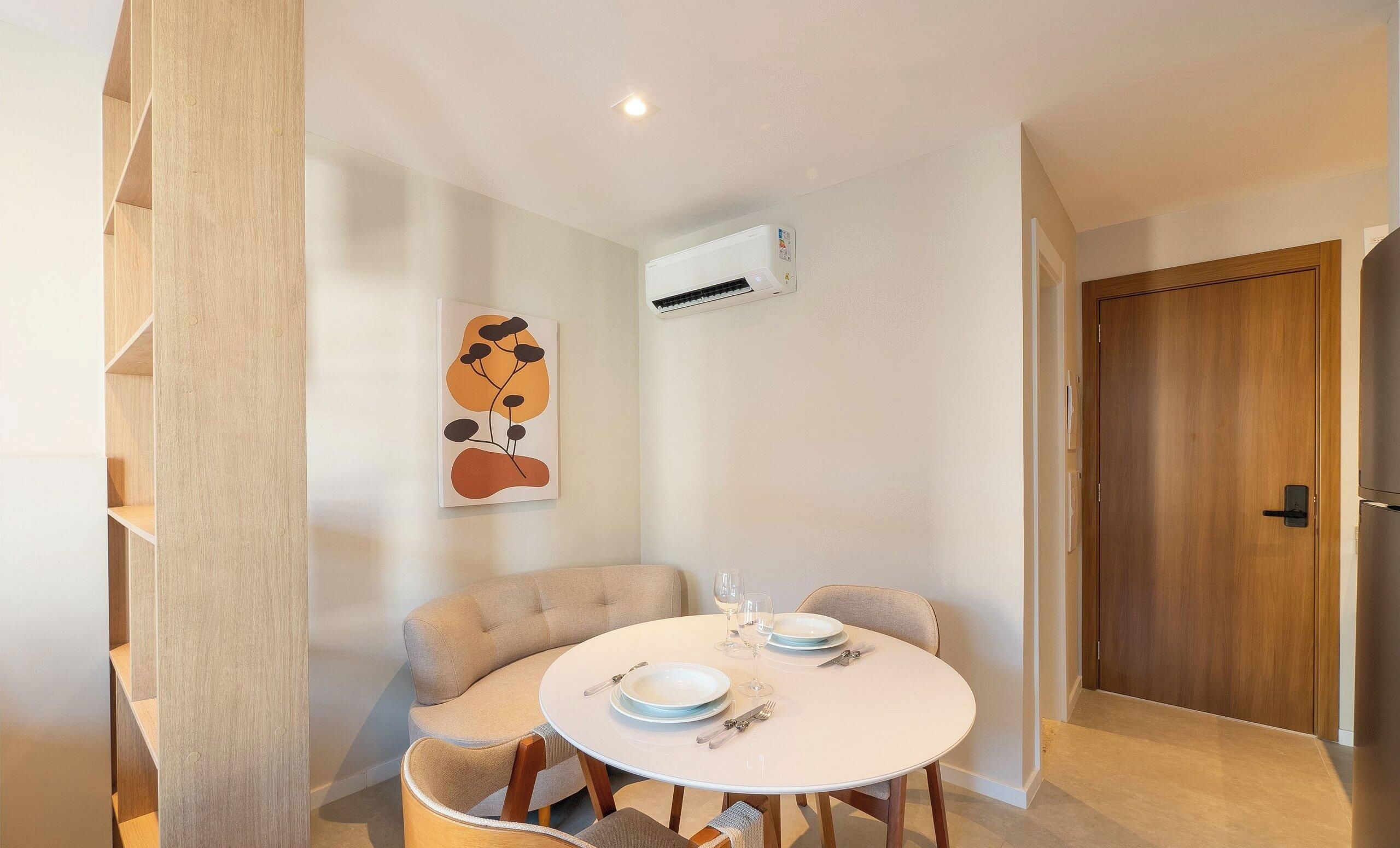 Een eetgedeelte met een ronde tafel, stoelen en een wandairconditioner.