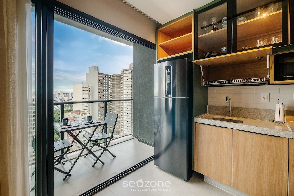 A modern kitchen with a built-in refrigerator, wooden shelves, and a balcony with a table and chairs.