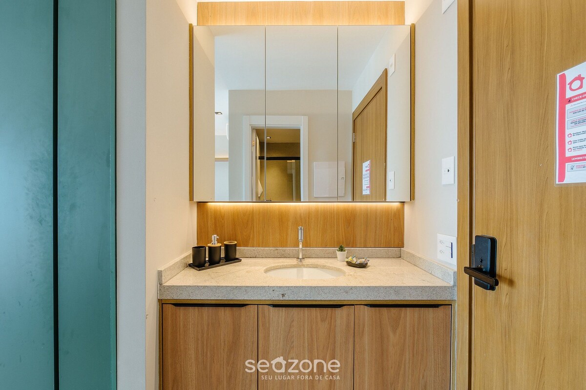 Un baño moderno con tocador de madera, lavamanos y espejo.