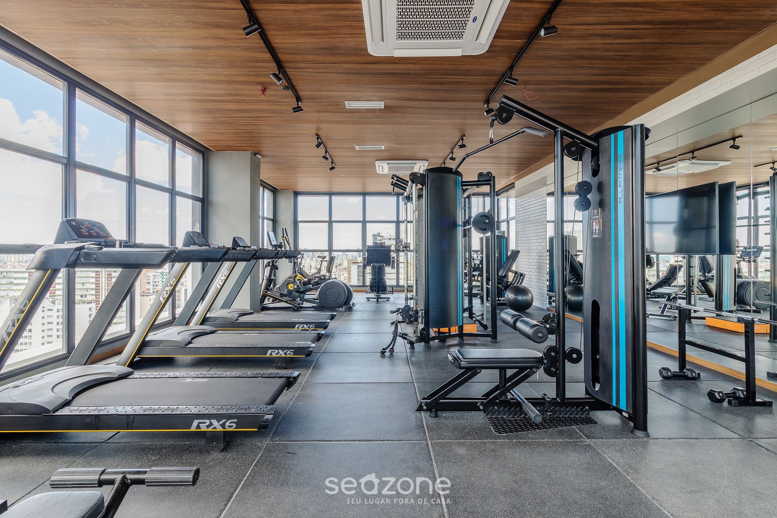 A gym with treadmills, weight machines, and a large mirror.