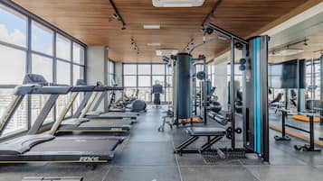 Une salle de sport équipée de tapis de course, d’appareils de musculation et d’un grand miroir.