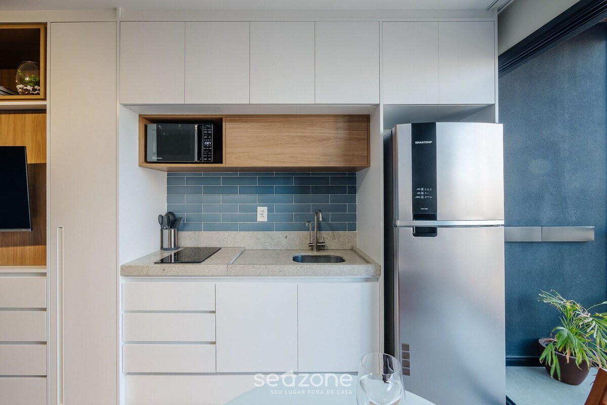 A modern kitchen with white cabinetry, a stainless steel refrigerator, a microwave, and a sink.