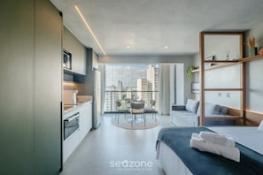 A modern hotel room with a kitchen, dining area, and a balcony with a city view. - Stay With Style and Convenience in Salvador LIV (Salvador)