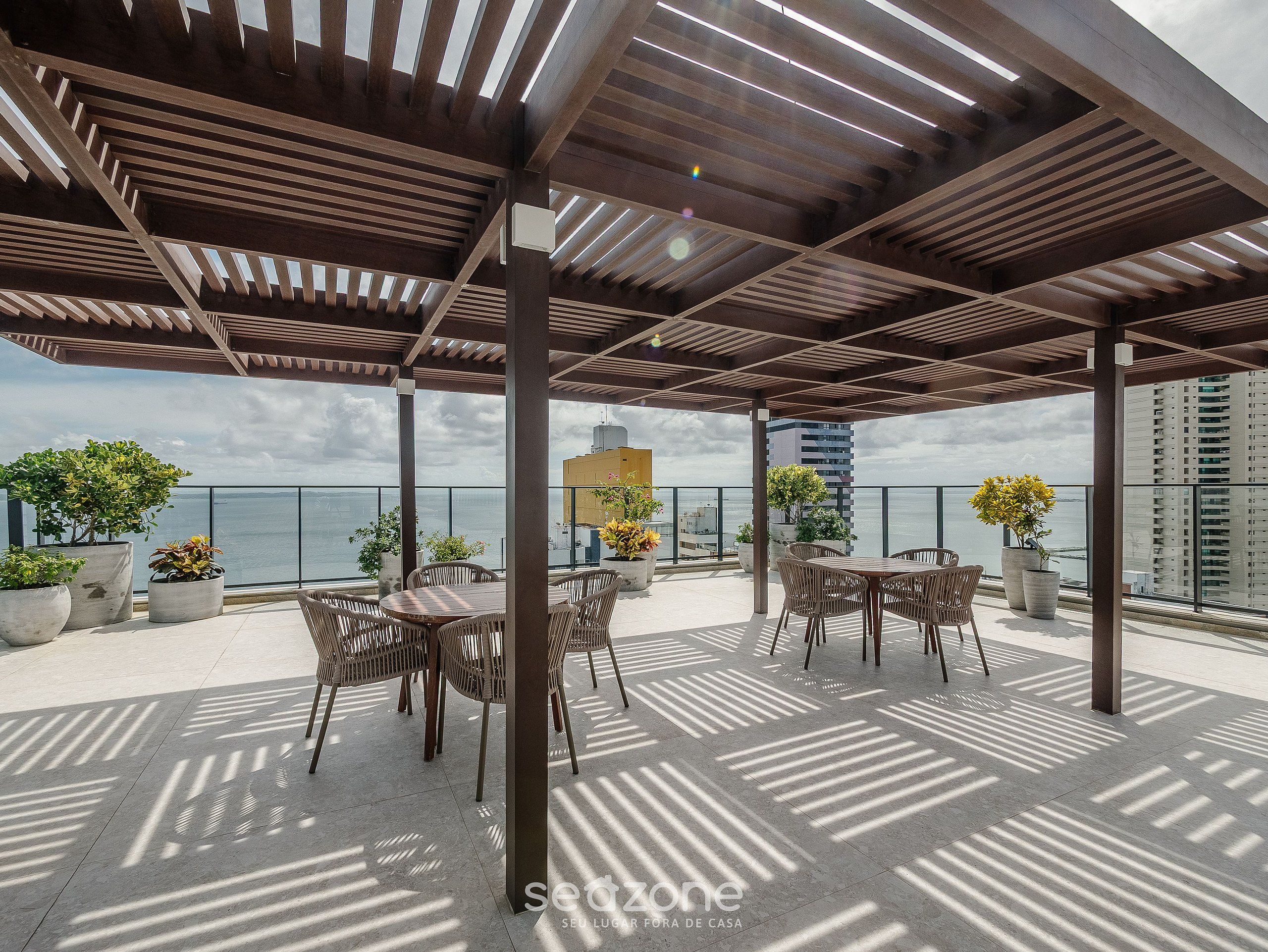 An outdoor patio with wooden pergola, potted plants, and tables and chairs.