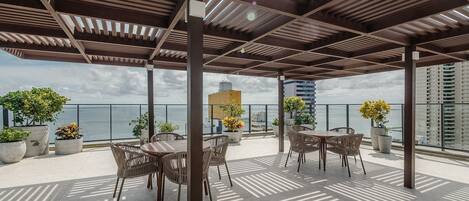 An outdoor patio with wooden pergola, potted plants, and tables and chairs.