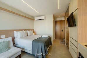 Une chambre d’hôtel équipée d’un lit, d’un canapé, d’un climatiseur, d’une télévision et d’une armoire en bois.