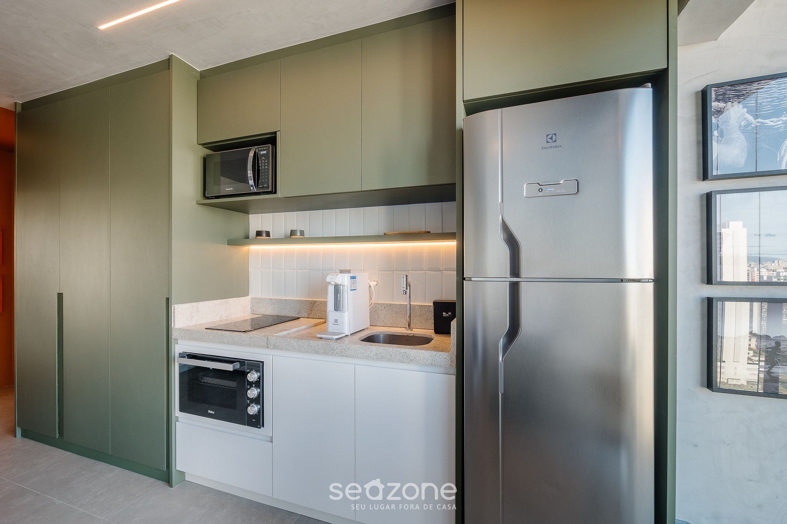 A modern kitchen with a built-in microwave, oven, and stainless steel refrigerator.
