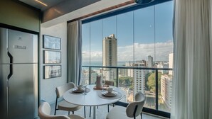 A modern dining area with a large window, a refrigerator, and framed pictures on the wall. - Stay With Style and Convenience in Salvador LIV (Salvador)