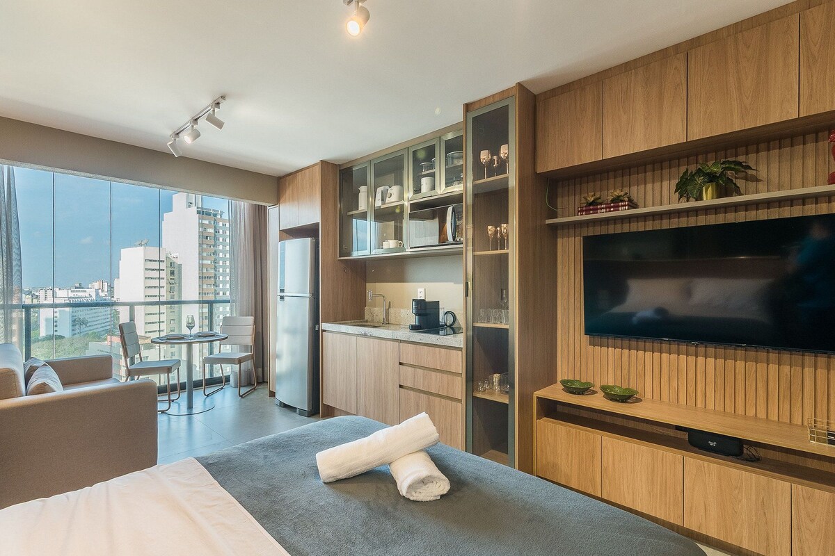 Una habitación de hotel moderna con balcón, comedor y televisor.