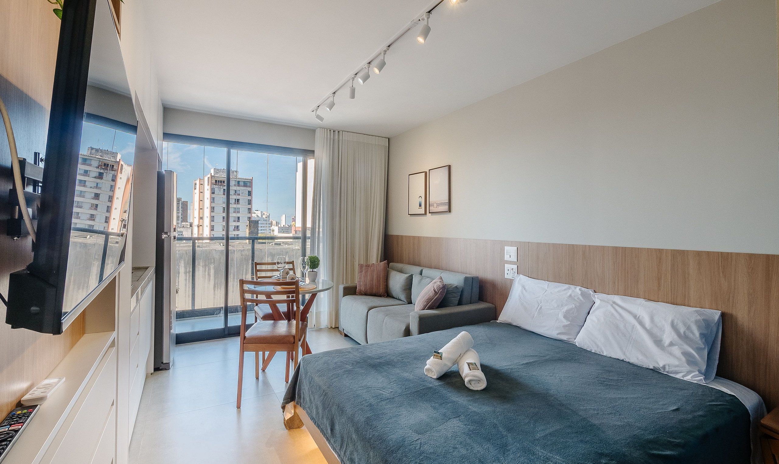 Una habitación de hotel con balcón, cama, sofá y zona de comedor.