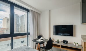 Une chambre d’hôtel moderne dotée d’un balcon, d’un coin repas, d’une t élévision à écran plat et d’une petite plante.