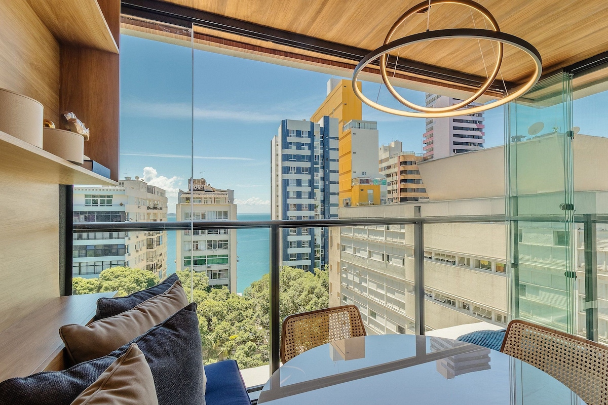 A modern interior with a glass balcony, a round light fixture, and a view of the cityscape.