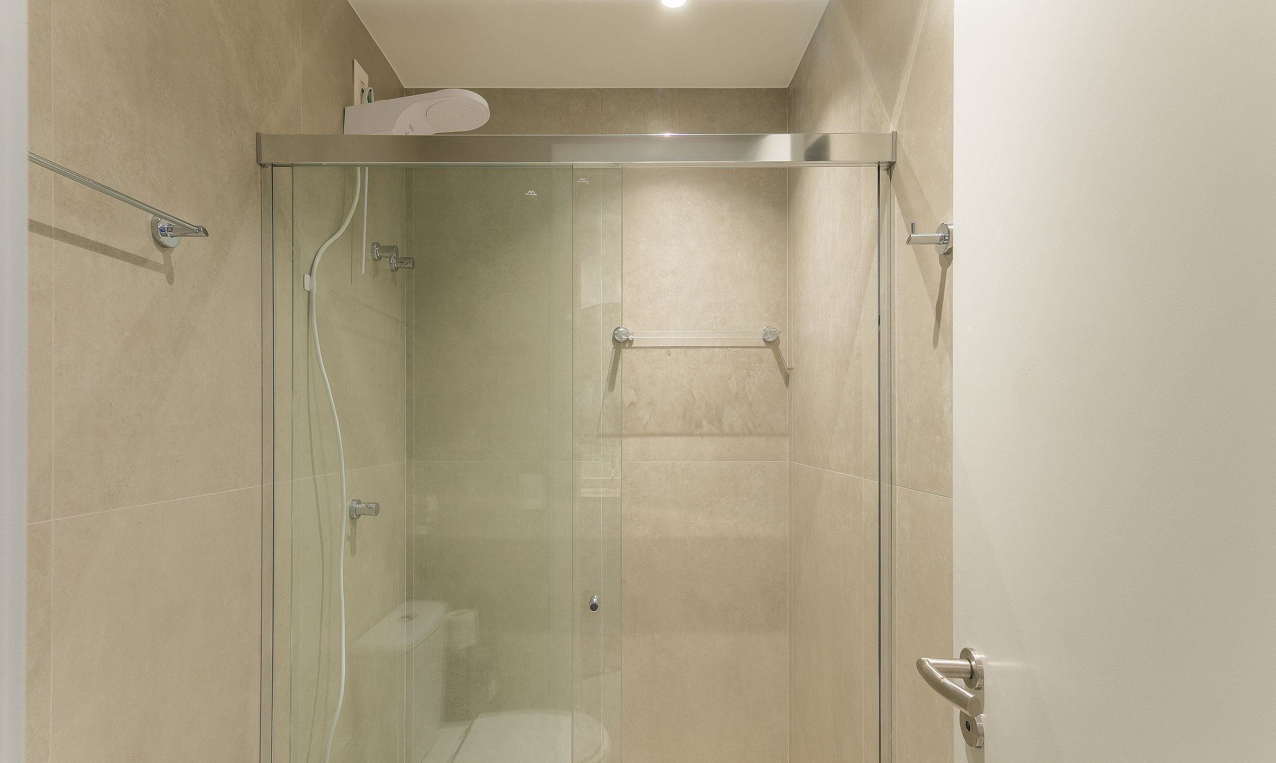 Une cabine de douche fermée par des parois en verre, équipée d’un porte-serviettes, de toilettes et d’un pommeau de douche.