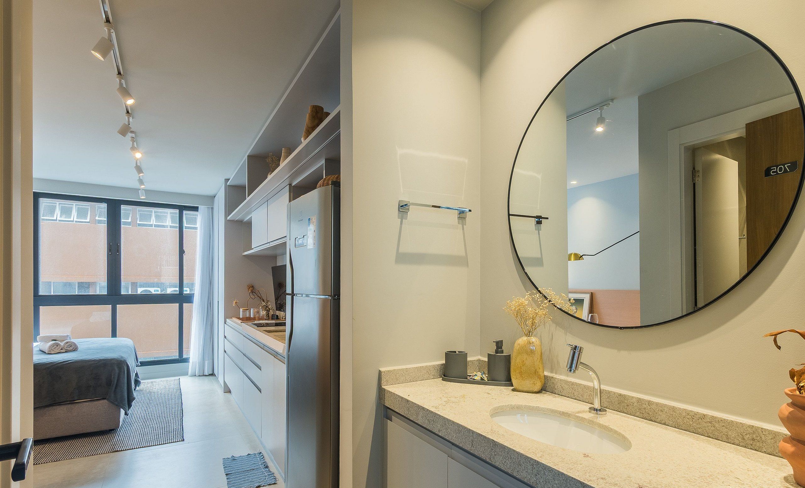 A modern bathroom with a large round mirror, a sink, and a toilet.