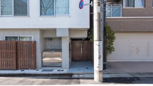 A building with a closed garage door, a no parking sign, and a utility pole with a hose. - Fare Metallo Hote 1-Tatami bedroom 201, Nakano City, Near Shinjyuku (Nakano City)