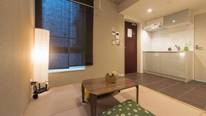 A compact living space with a dining area, kitchenette, and a large window with blinds. - Fare Metallo Hote 1-Tatami bedroom 201, Nakano City, Near Shinjyuku (Nakano City)