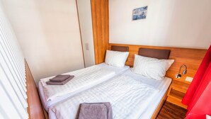 Ein Doppelbett mit weißen Bettwäsche, zwei Kissen und zwei gefaltete Handtücher.