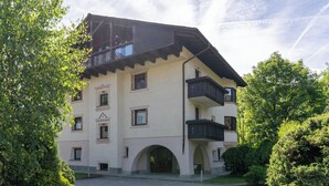 A multi-story building with a balcony on the second floor, a central entrance with an archway, and a surrounding garden. - Milano 27 - Two Bedroom Apartment, Sleeps 4 (Bormio)