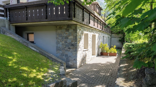 A stone building with a wooden balcony, a paved pathway, and potted plants. - Milano 27 - Two Bedroom Apartment, Sleeps 4 (Bormio)