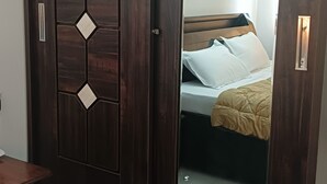 Une armoire avec un miroir, un lit avec une literie blanche et un tapis vert avec une télécommande.