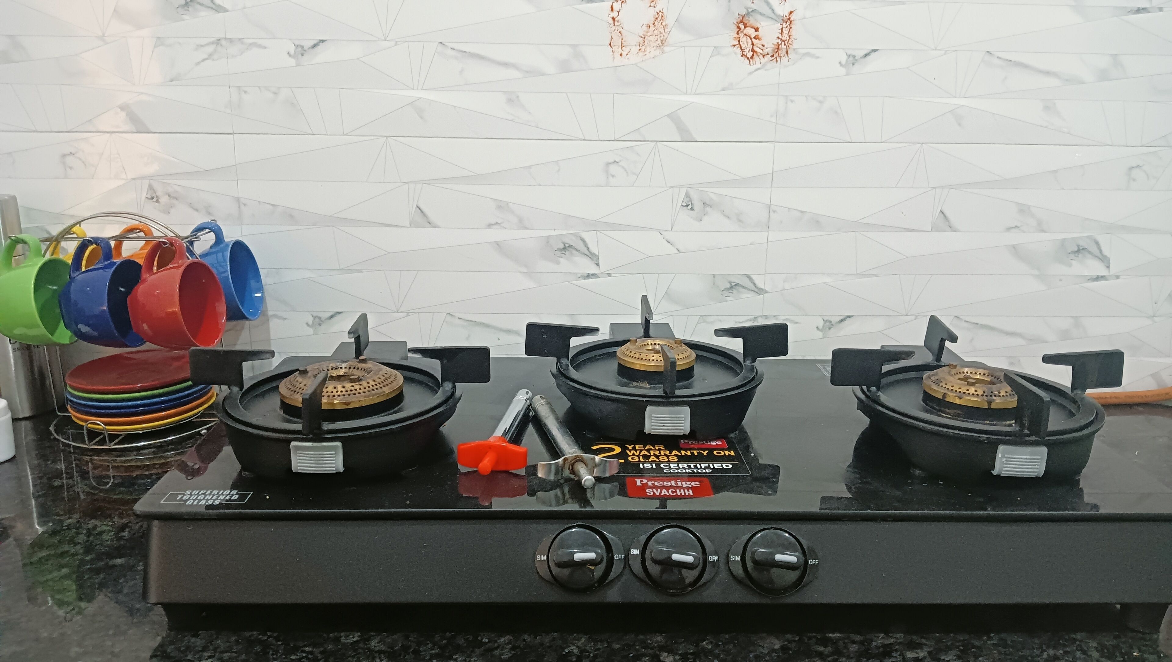 A kitchen with a black stove, three burners, and a gas supply.