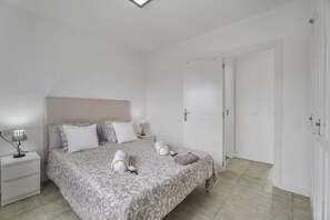 A bedroom with a bed, nightstands, and a door.