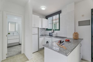 A modern kitchen with white cabinets, a built-in washing machine, a microwave, and a granite countertop. - Vacation 'Costa Serena' with Mountain View, Shared Pool and Wi-Fi (Arona)