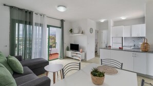 Eine moderne Wohnung mit Wohnzimmer, Essbereich, Küche und einem Balkon mit Blick.