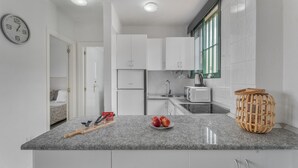 Eine moderne Küche mit weißen Schränken, einer Granitarbeitsplatte, einer Mikrowelle und einem Korbwäscheschrank.