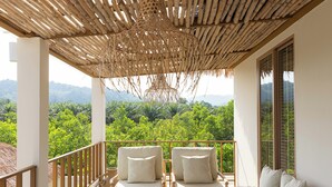 Un balcone con mobili in vimini e vista su un verdeggiante paesaggio.
