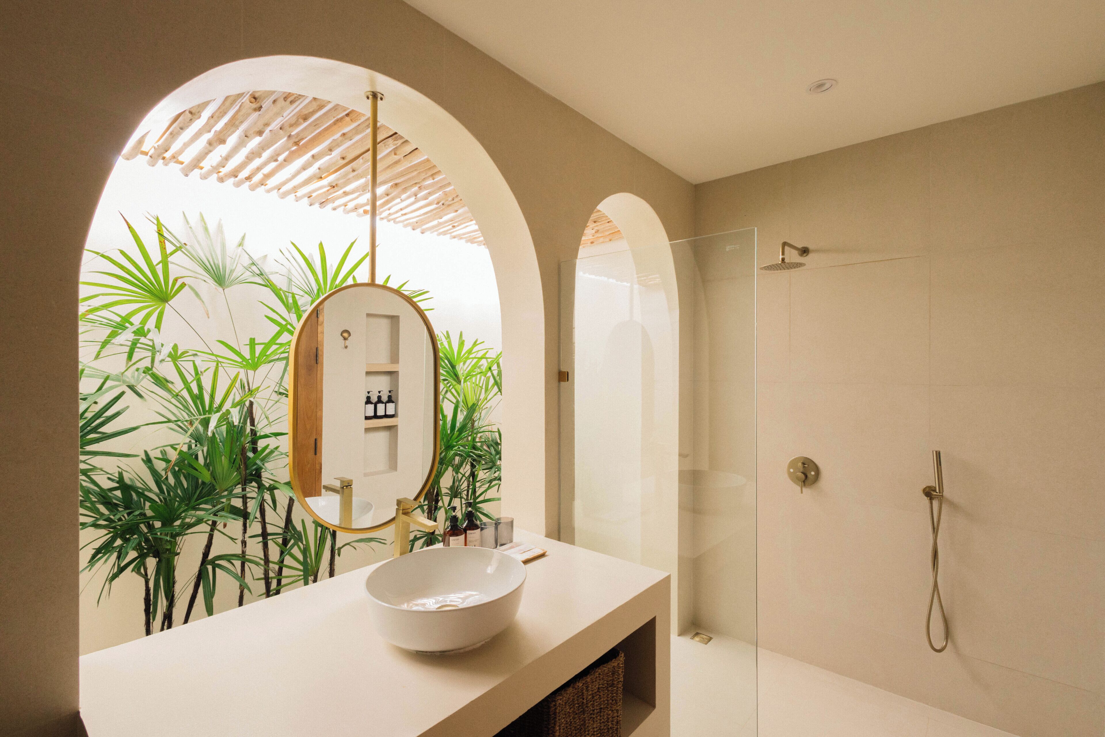 A modern bathroom with a large white sink, a mirror, and a glass-enclosed shower.