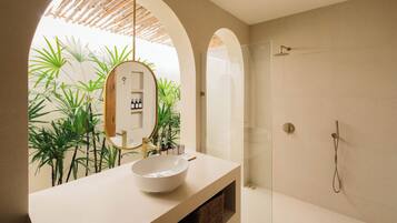 A modern bathroom with a large white sink, a mirror, and a glass-enclosed shower.