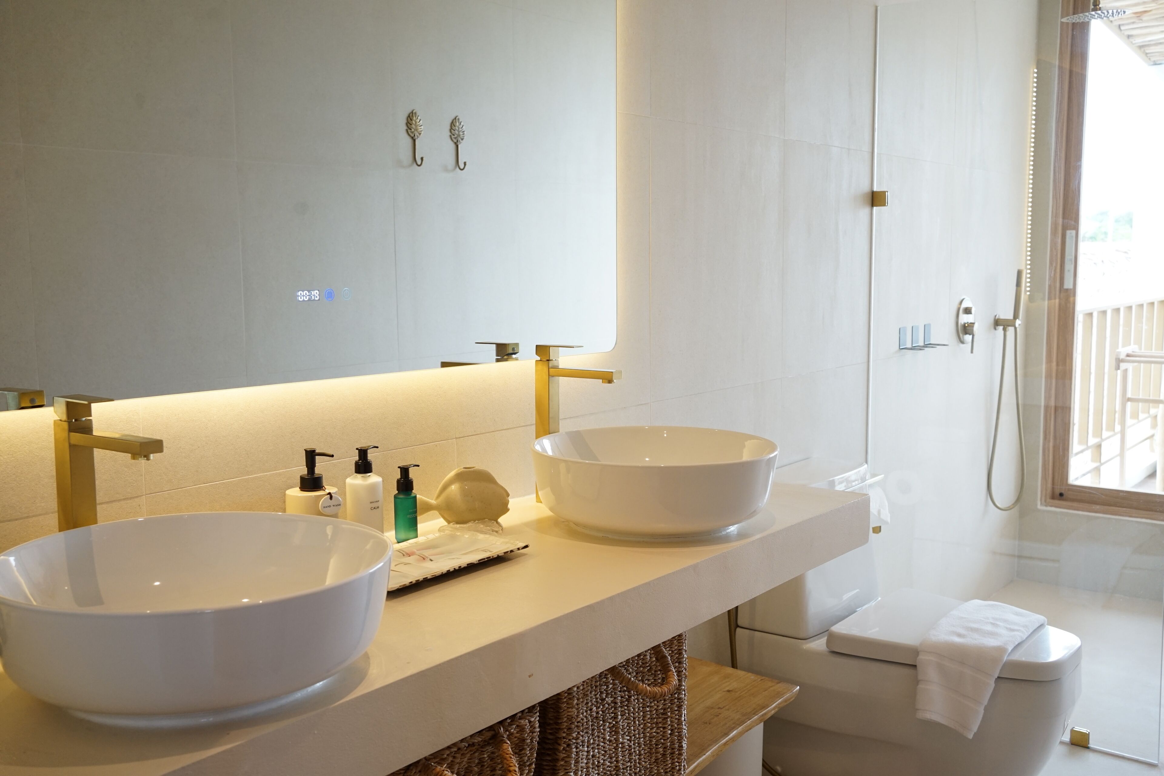 Un baño moderno con dos lavamanos grandes blancos, una ducha y un inodoro.