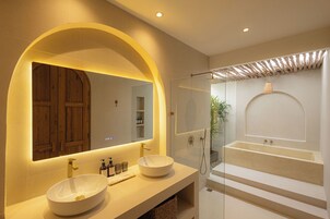 Un baño moderno con un espejo grande, dos lavamanos y una bañera.