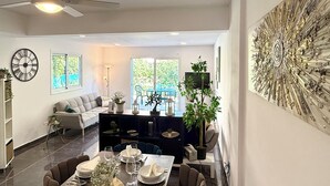 A modern dining area with a long table set for six, a sofa, and a decorative wall piece.