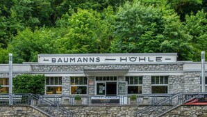 Un edificio con fachada de piedra, un letrero que dice 'BAUMANNs - HOHLE' y una escalera que lleva a la entrada.